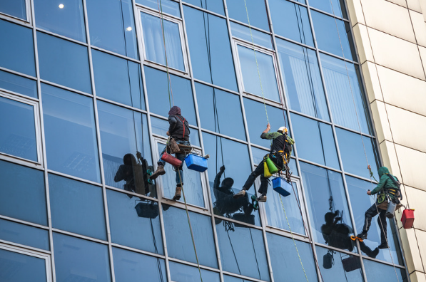 window cleaners on side of commercial real estate building