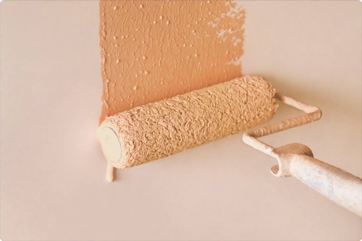 orange paint roller applying paint to wall